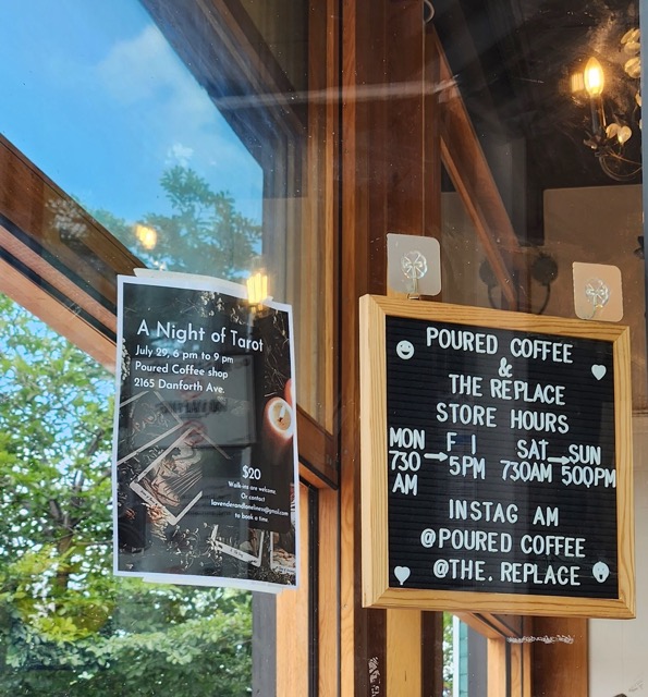 Cafe sign in a bright window, a poster for a Tarrot reading is beside 